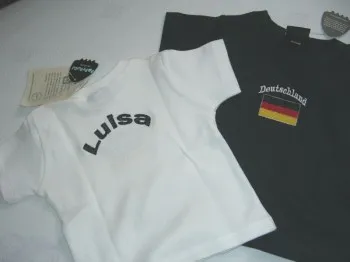 Weisses oder schwarzes T Shirt fuer dein Baby mit Namen und Laenderkennzeichnung bestickt.