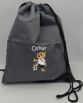 Dunkelgrauer Turnbeutel mit dem Namen Oskar in Weiß und einem gestickten Fußballbären im Deutschlandtrikot mit Fußball