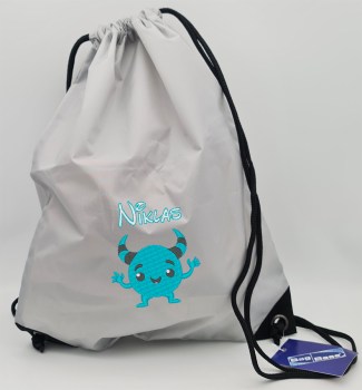 Hellgrauer Turnbeutel mit türkis gesticktem Namen Niklas und einem niedlichen türkisfarbenen Monster mit Hörnern als Stickmotiv