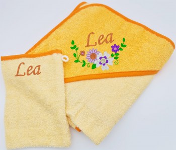 Set Kapuzentuch in zartgelb mit einer Blumenranke und dem Namen auf der Kapuze und dazu einen Waschhandschuh mit Name bestickt